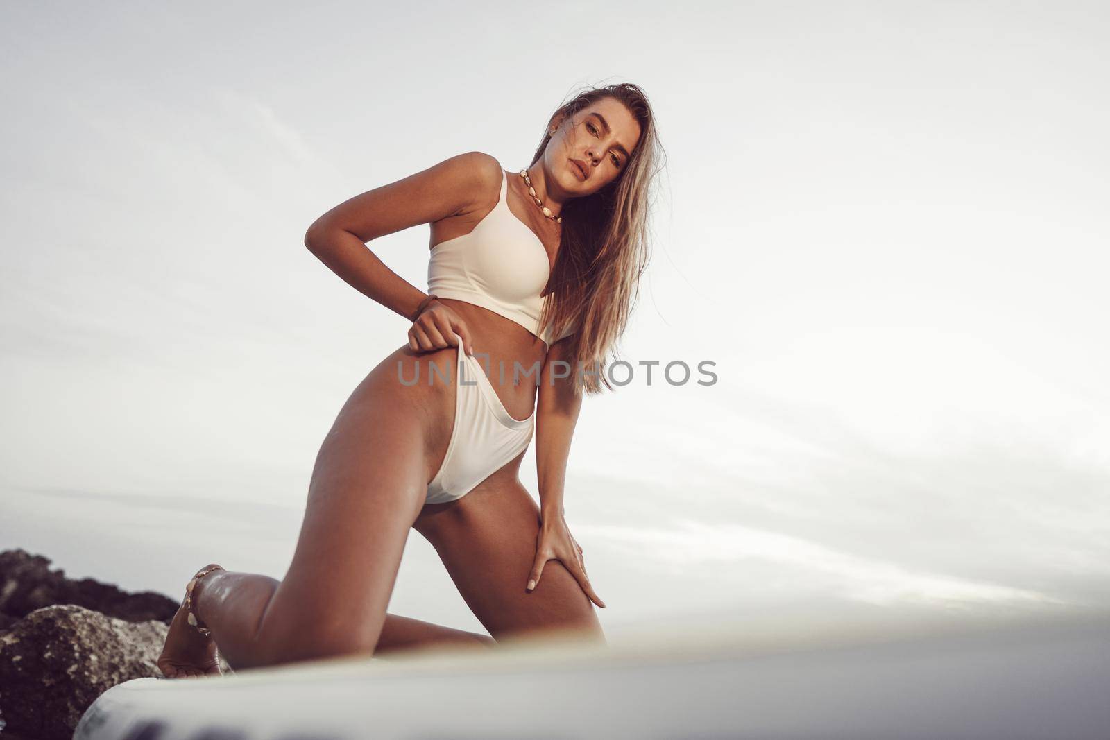 Young beautiful sexy woman posing in the sea on a SUP board