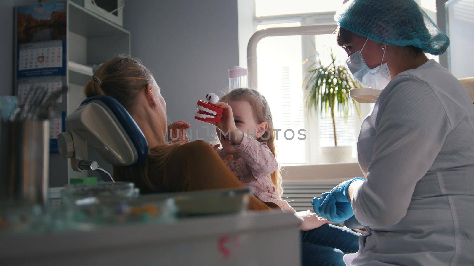 Girl, her mom and the dentist in the dental office, the stomatologist advising with a special toy by Studia72