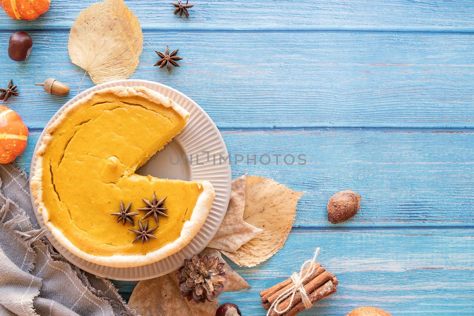 Autumn concept. Homemade pumpkin pie with autumn leaves on rustic background, top view flat lay