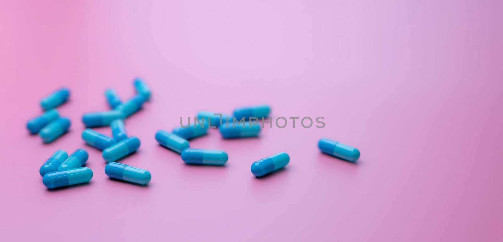 Selective focus on blue capsule pills on pink background. Pharmacy banner. Online pharmacy concept. Pharmacy drugstore product. Pharmaceutical industry. Capsule pills for the pharmaceutical industry.