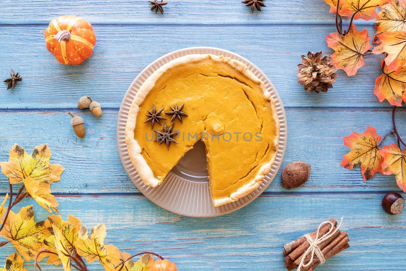 Autumn concept. Homemade pumpkin pie with autumn leaves on rustic background, top view flat lay