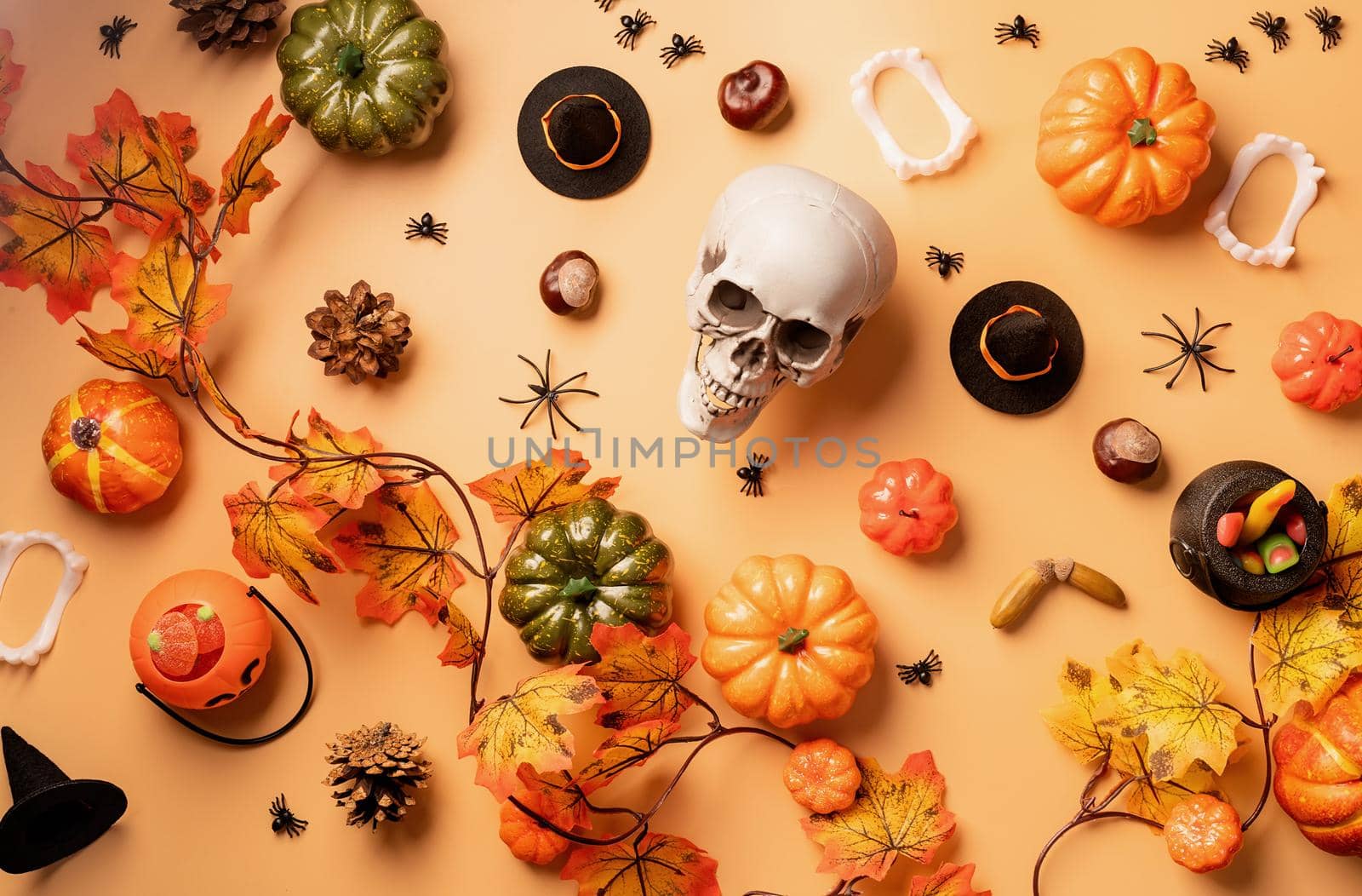 Halloween concept. Halloween holiday decorations with pumpkins and candies top view on orange background