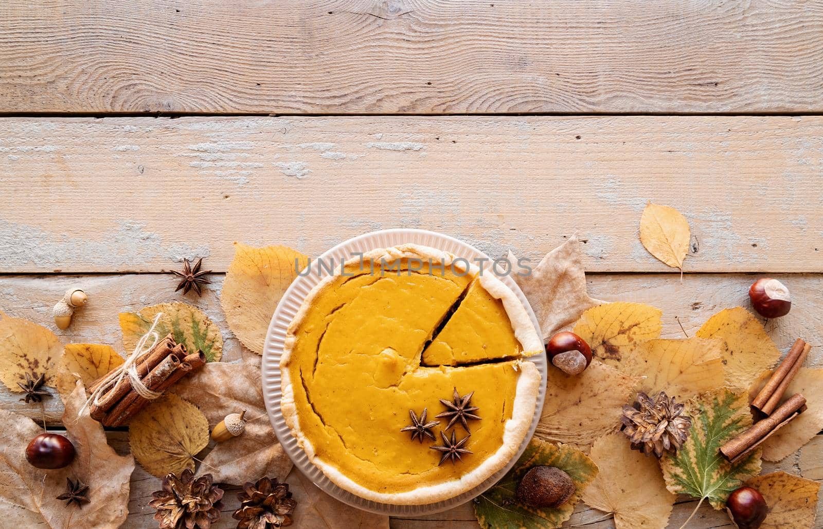 Autumn concept. Homemade pumpkin pie with autumn leaves on rustic background, top view flat lay