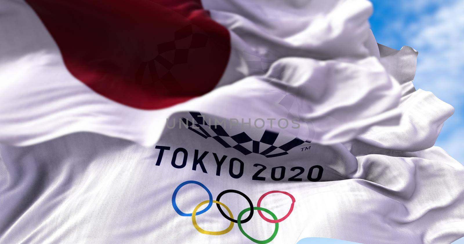 Tokyo, Japan, July 2021: Tokyo 2020 olympic flag waving with the Japanese flag blurred in the foreground. Selective focus. Tokyo 2020 olympics games were postponed to 2021 due to the covid-19 pandemic