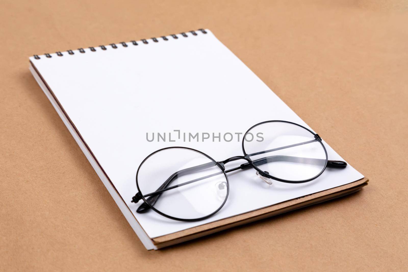 Stationary concept, Flat Lay top view Photo of glasses and notepad on a beige abstract background with copy space, minimal style