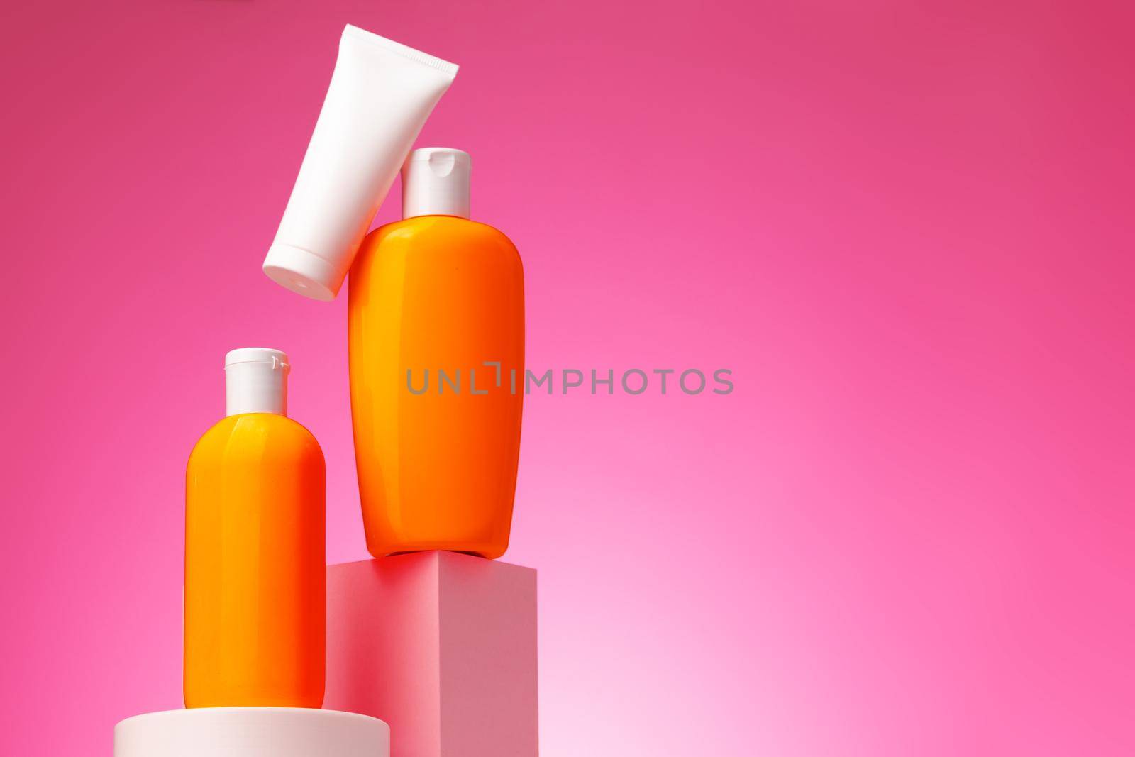 Skincare beauty products container against pink background, copy space