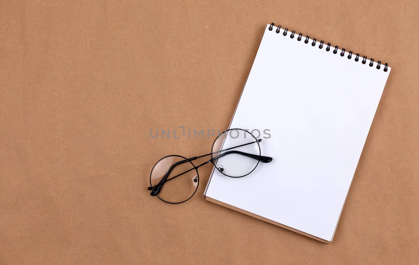 Stationary concept, Flat Lay top view Photo of glasses and notepad on a beige abstract background with copy space, minimal style