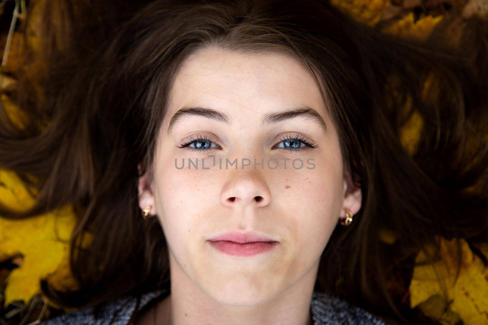 Top view of a cute girl with blue eyes, which in the fall lies on the ground