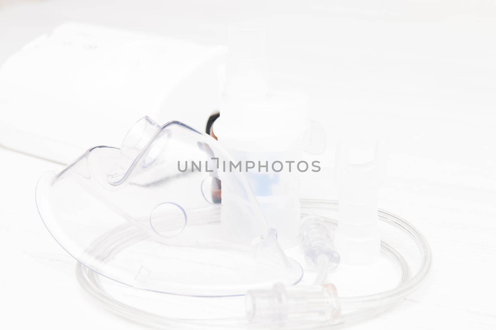 nebulizer and accessories for it on a light background, copy space, inhaler and mask, medicine for inhalation, compressor type by natashko