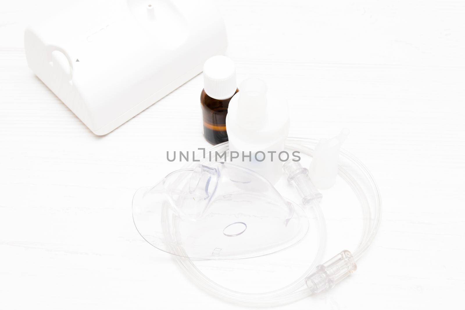 inhaler, tube and mask with a large palat on a light background, copy space, medicine in a dark bottle for inhalation, respiratory diseases concept, top view
