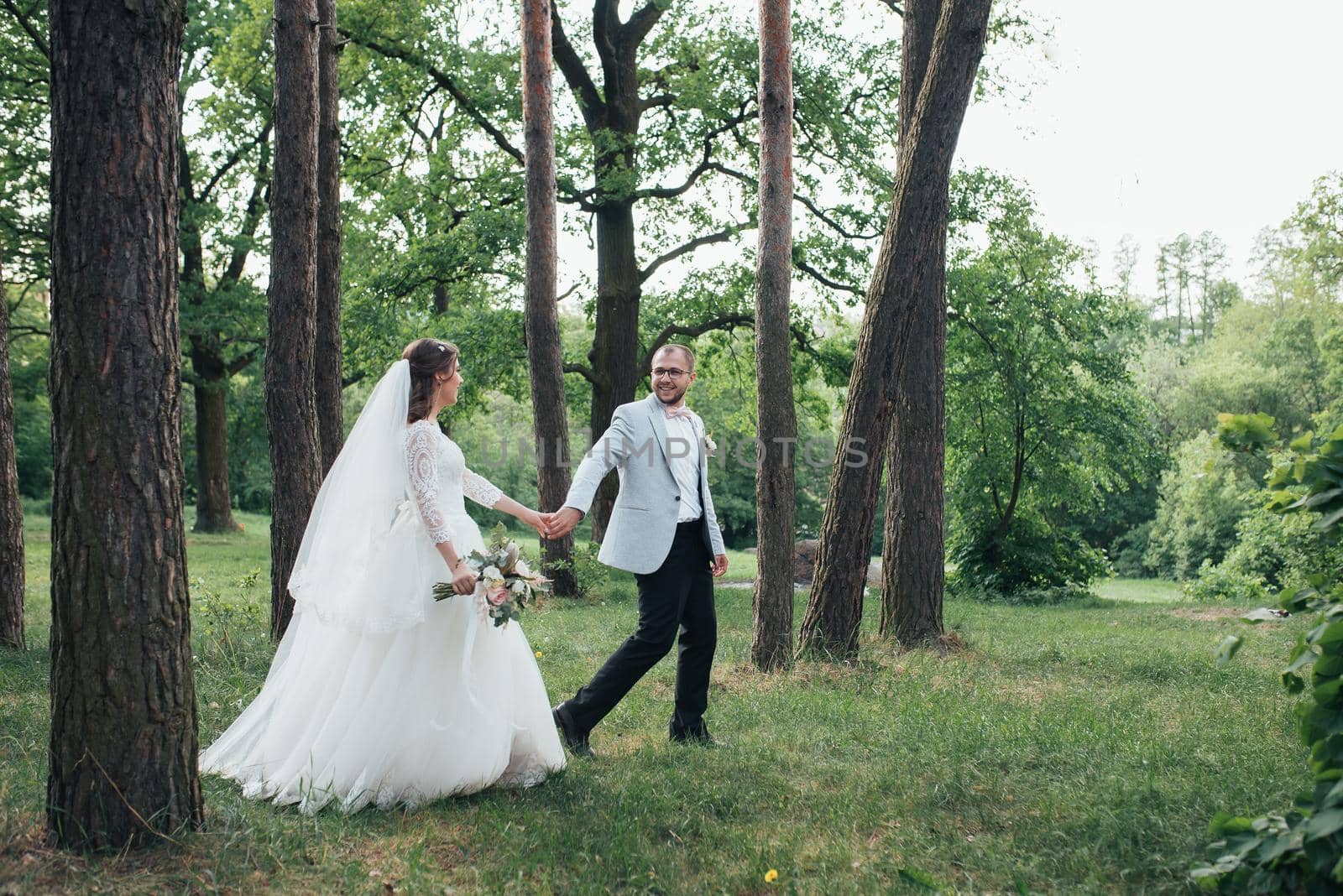 Bride and groom are walking in the woods on their wedding day. by lunarts