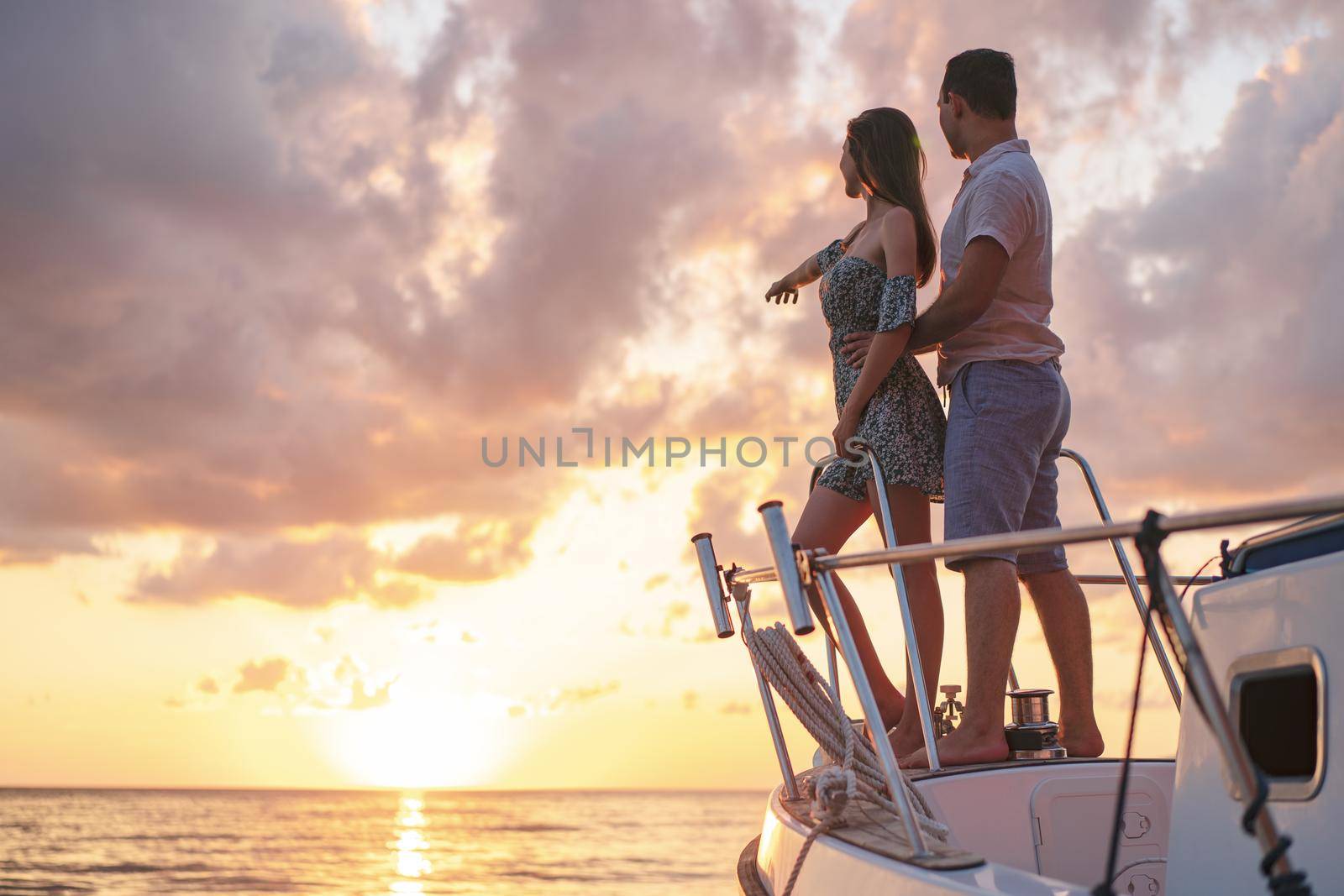Beautiful couple looking at sunset from the yacht by Fabrikasimf