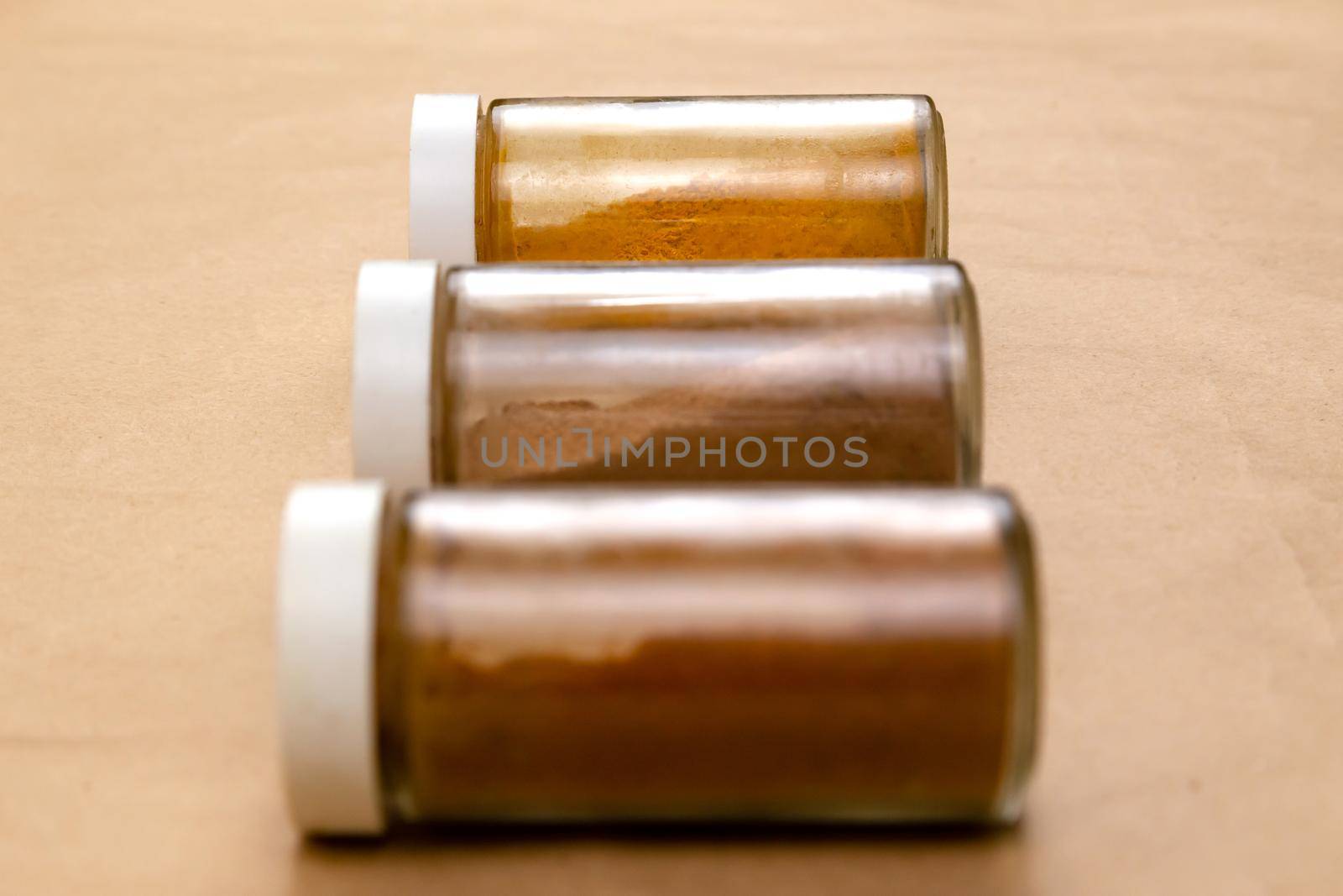 Three jars of seasoning on a brown background with selective focus