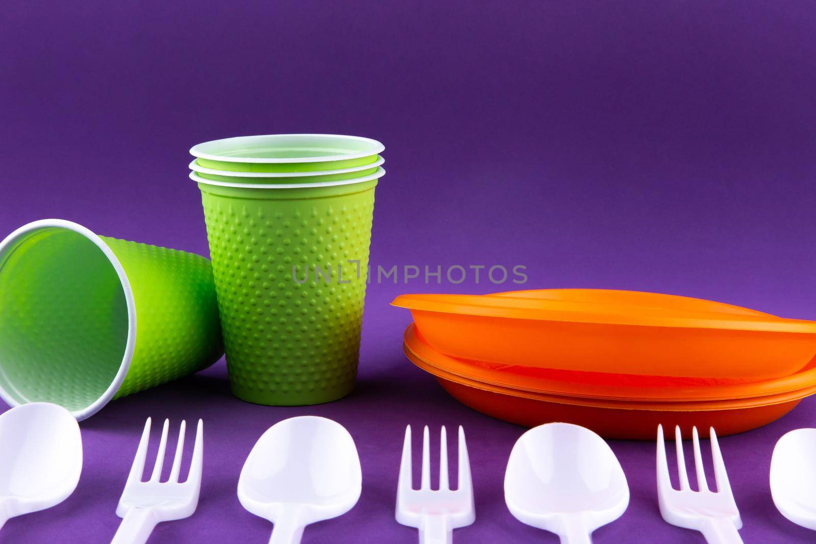 Plastic orange green waste collection on purple background. Concept of plastic pollution and ecology problem. by lunarts