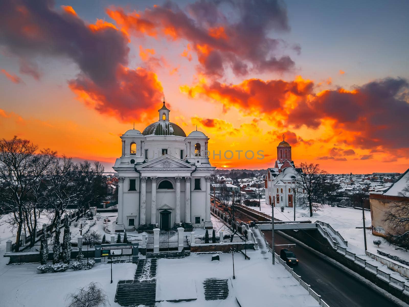 Aerial view of the cathedral and church in snow-covered small european city at bright winter sunset Gorgeous sunset and clouds.. Drone. Winter. Ukraine, 2021