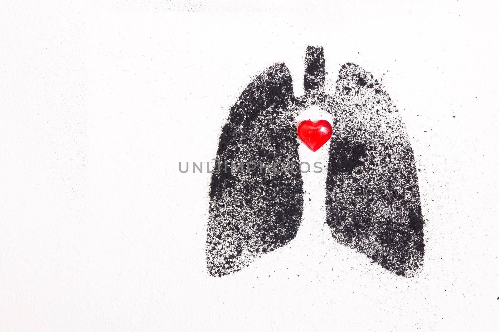 silhouette of human lungs from coal dust on a white background, lungs from pieces of coal and a small red glass heart, health care concept, respiratory diseases, copy space