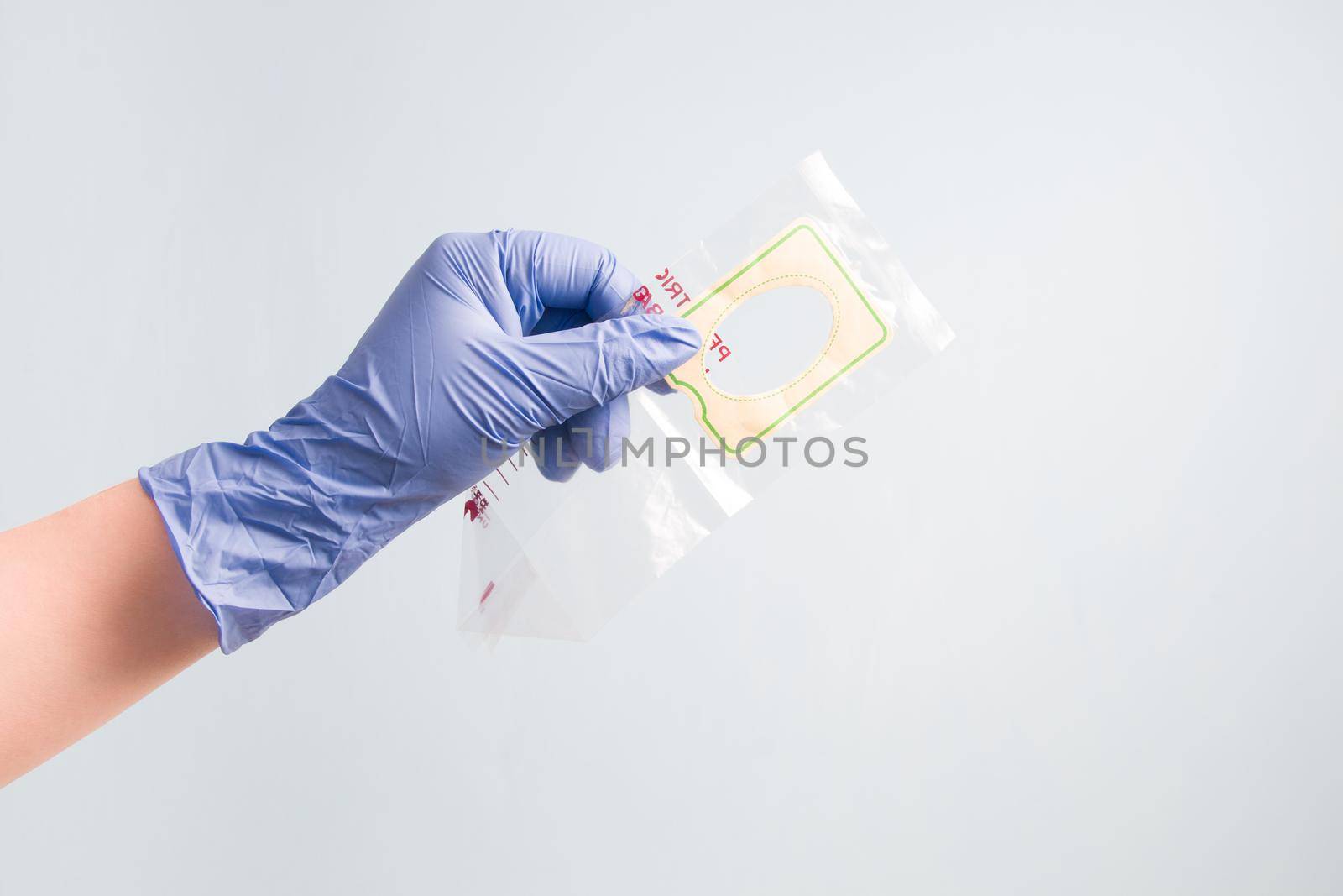 hand in blue disposable medical rubber glove pediatric holds an empty urine bag, bag for collecting urine in children, blue background, copy space by natashko
