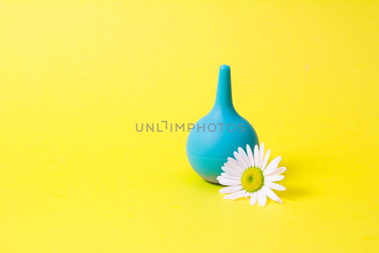 green small enema and chamomile on yellow background