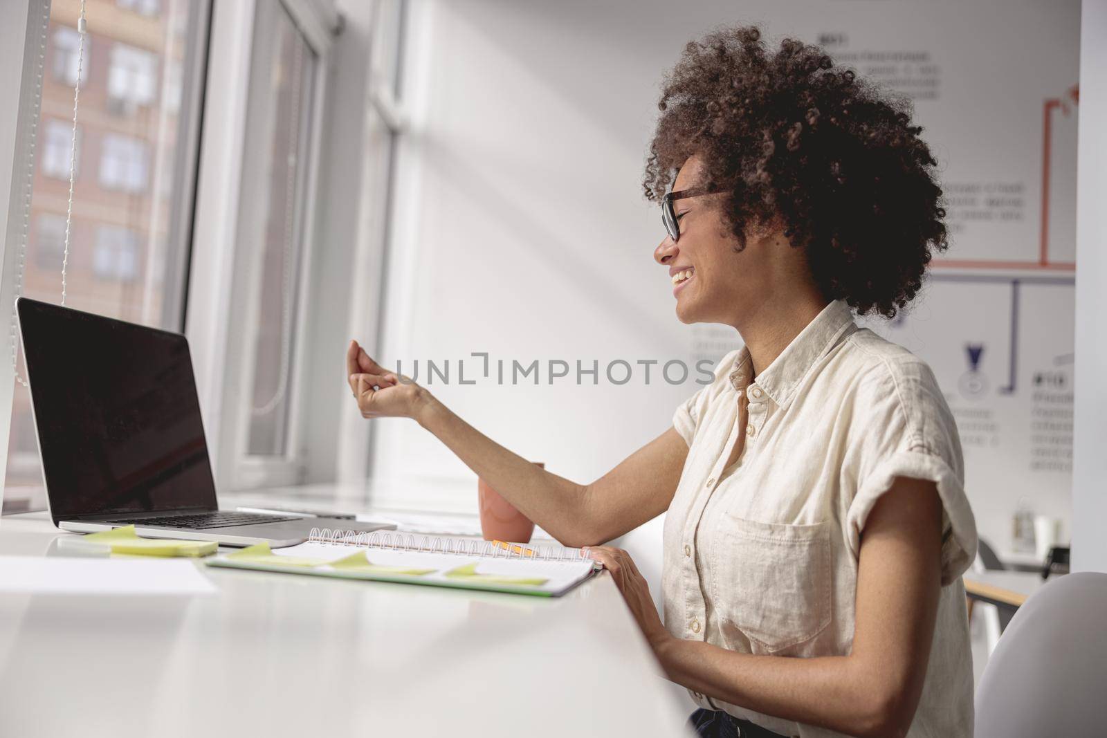 Side view of smiling woman communicating in sign language online while looking at laptop screen