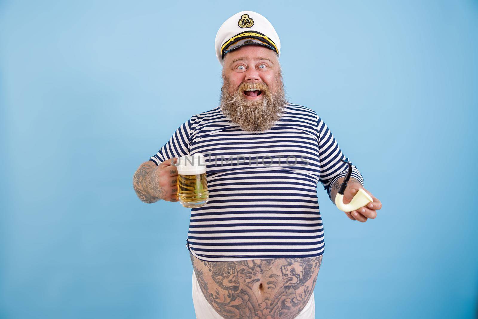 Joyful plus size person in sailor suit holds pipe and beer on light blue background by Yaroslav_astakhov