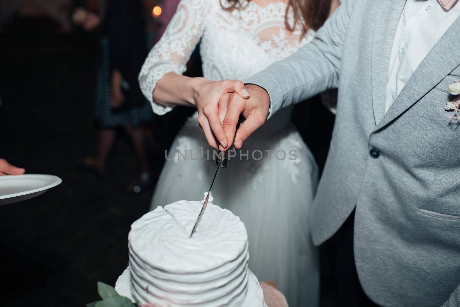 The bride and groom at the party cut and try the wedding cake.