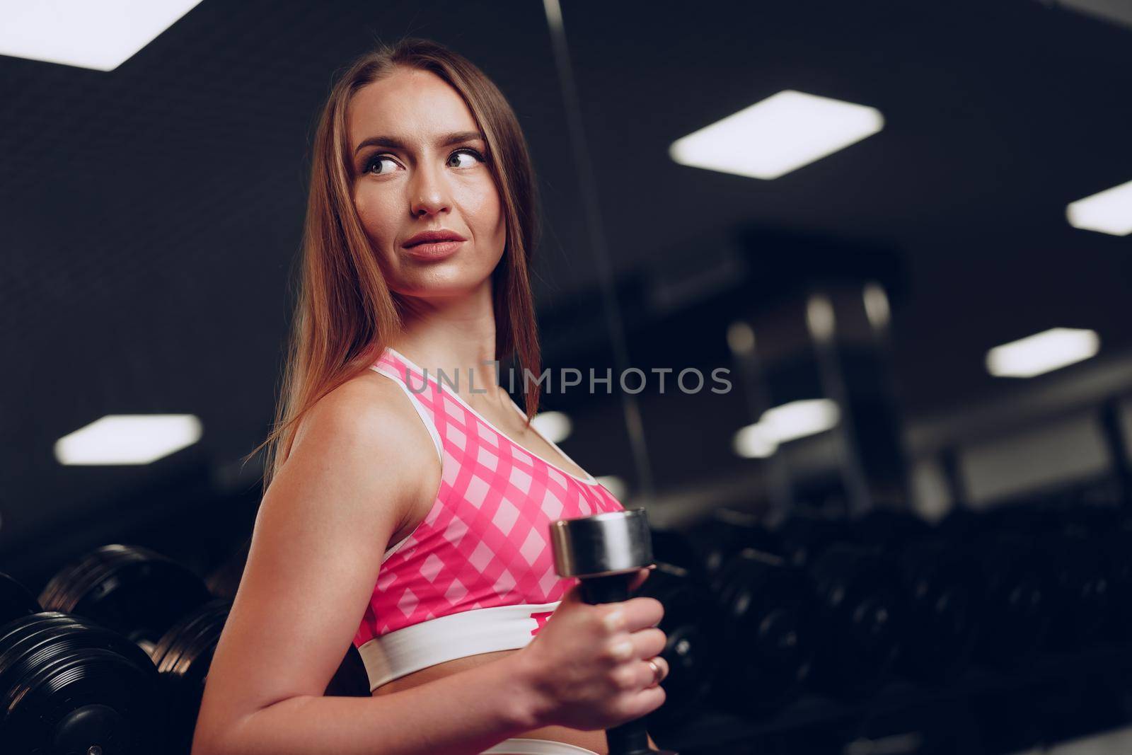 Portrait of a young woman in sportswear posing in a dark gym