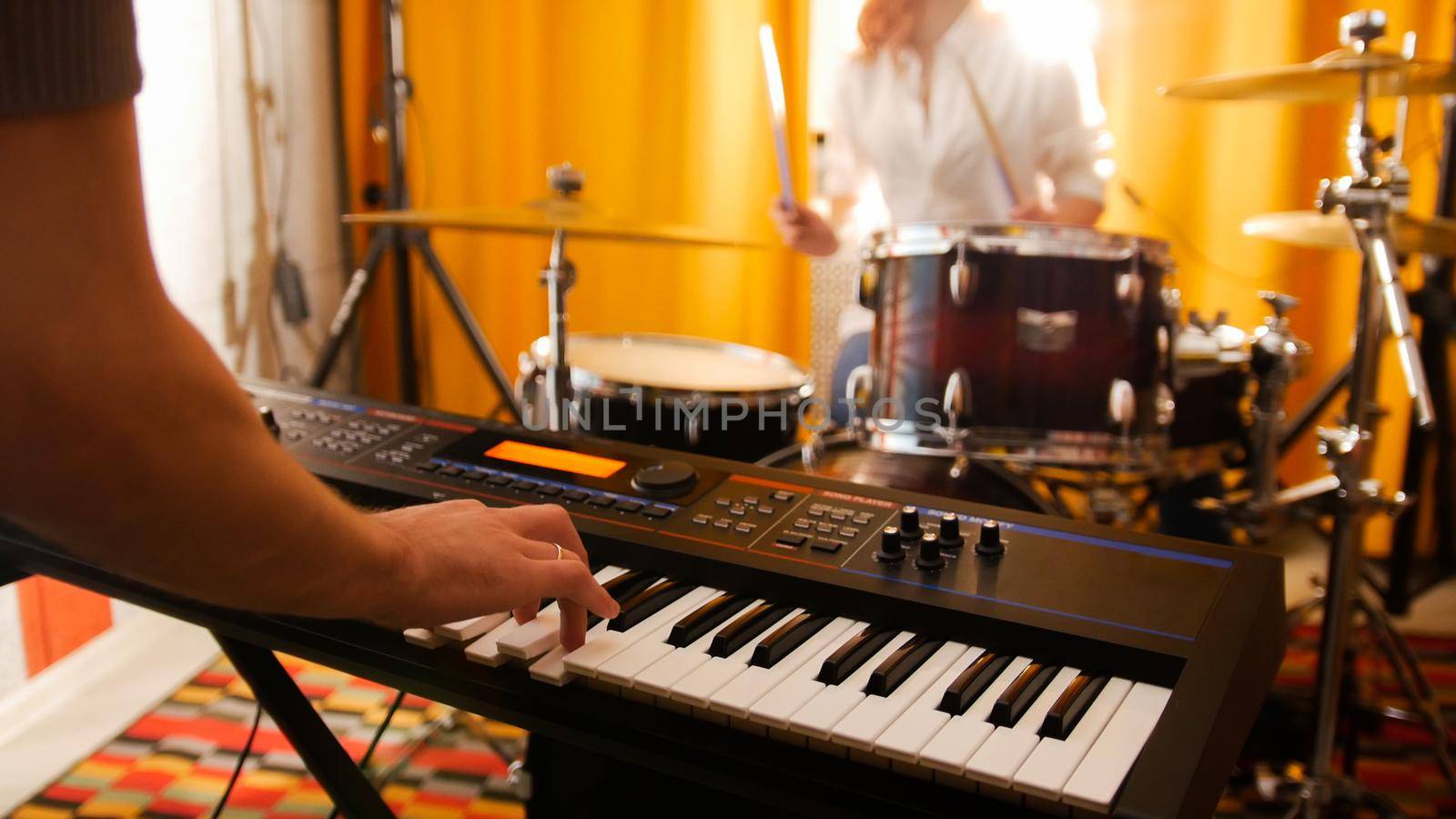 Repetition. Girl drummer and a guy on keyboards. Focus on keyboard. Studio