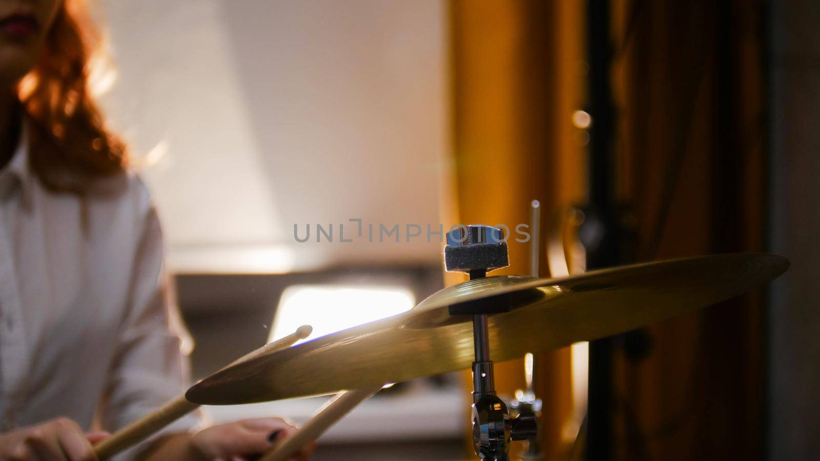 Repetition. Ginger girl plays drums. The girl hitting hi-hat. Studio