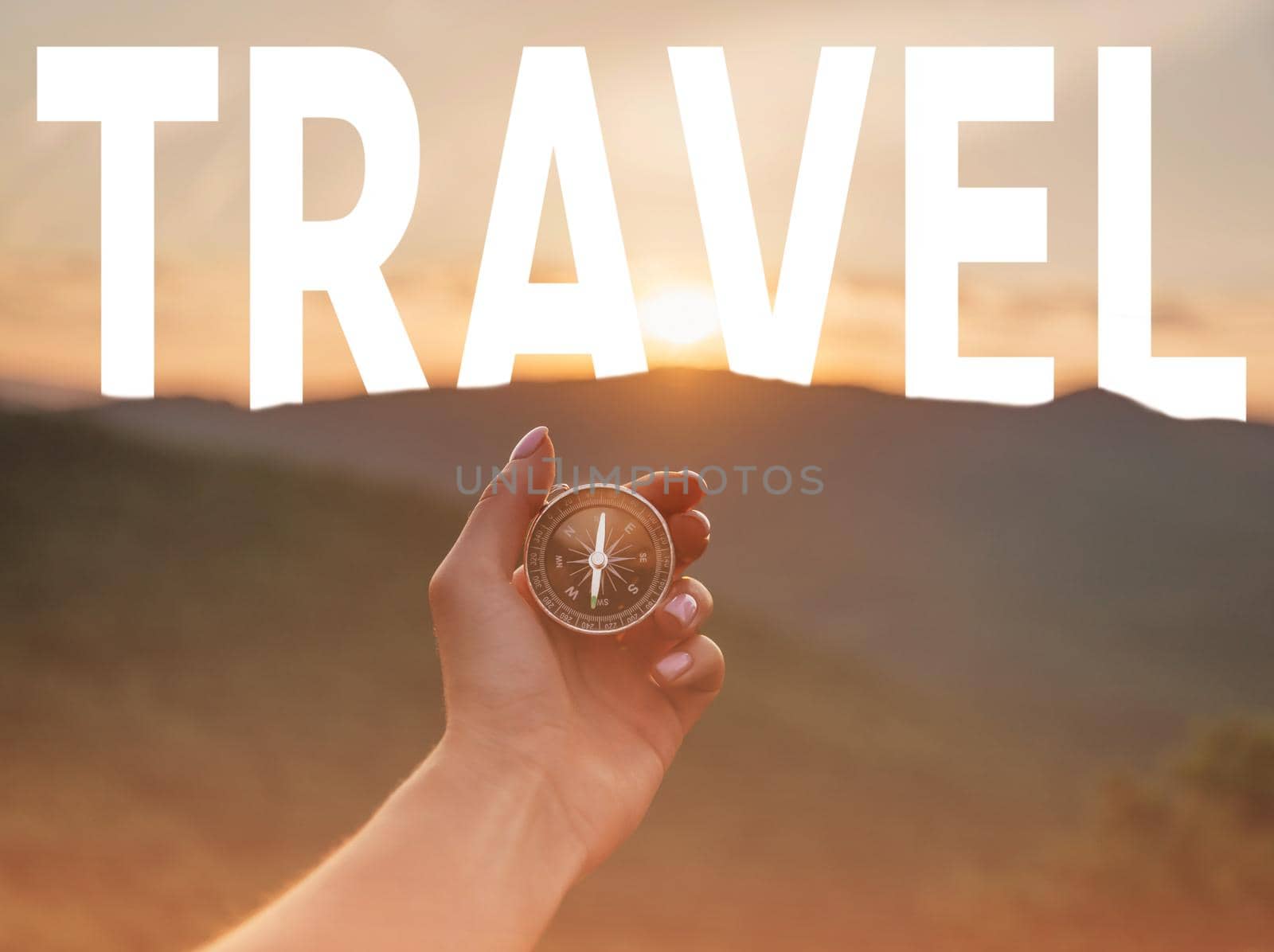 Unrecognizable woman holding compass in hand in summer mountains at sunrise, point of view in first person. Word travel in the sky.