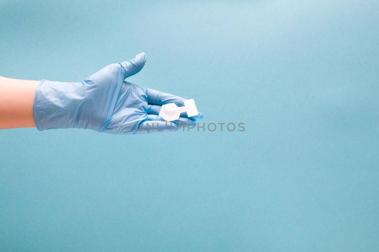 female hand in blue disposable medical glove holds containers with medication for inhalation, blue background copy space, treatment of asthma and bronchospasm, pulmonoligia concept by natashko