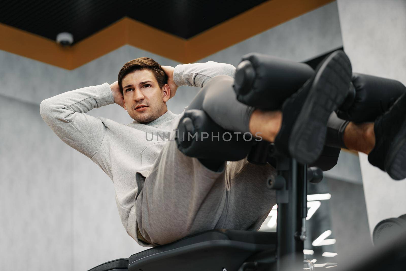 Young athlete doing abs exercises workout in modern gym, close up