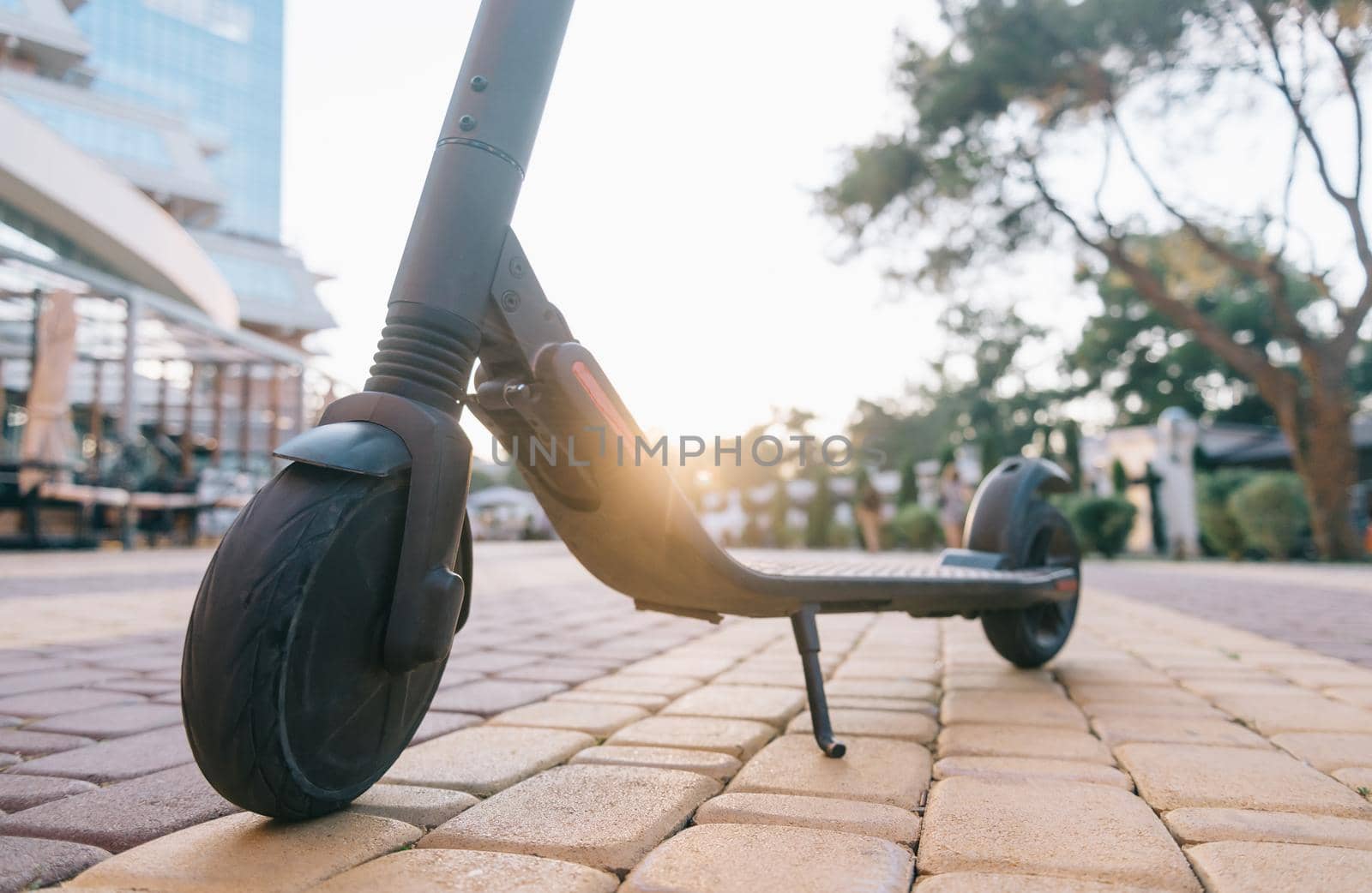 Electric scooter in city summer park at sunset.