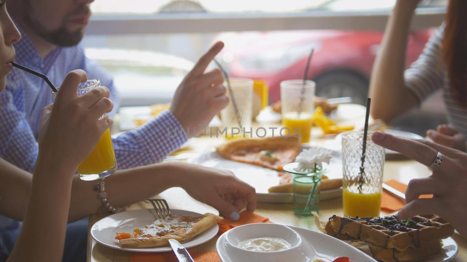 Young friends taking pizza cuts from plate on table in restaurant, close up