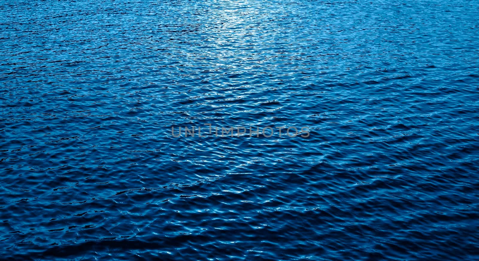 Small Water waves are moving in the sea. Texture or background. Evening sun in blue sea water. Trendy Banner with color of the year 2020
