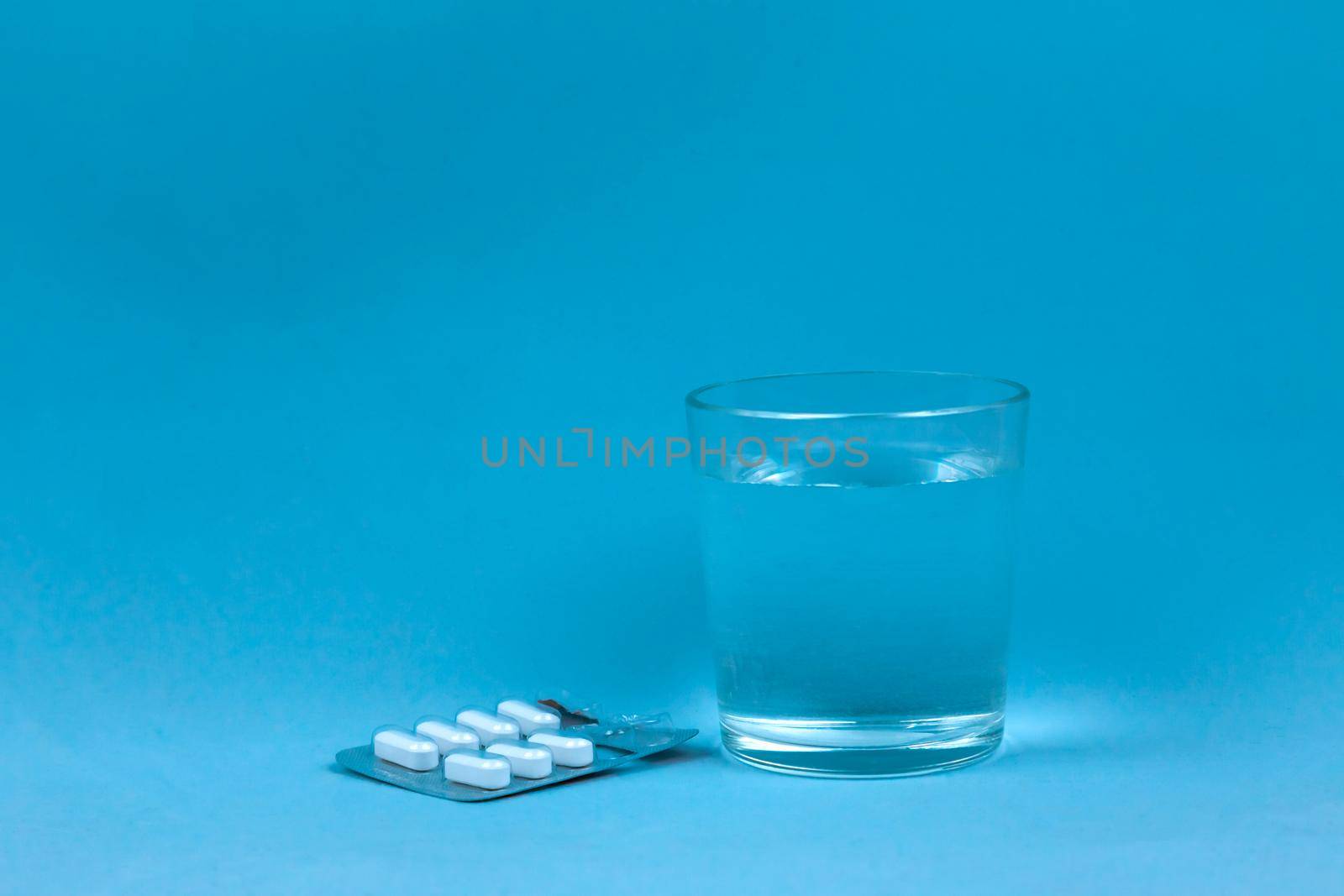 Glass Of Water And Pills On Blue Background with copy space for text by lunarts