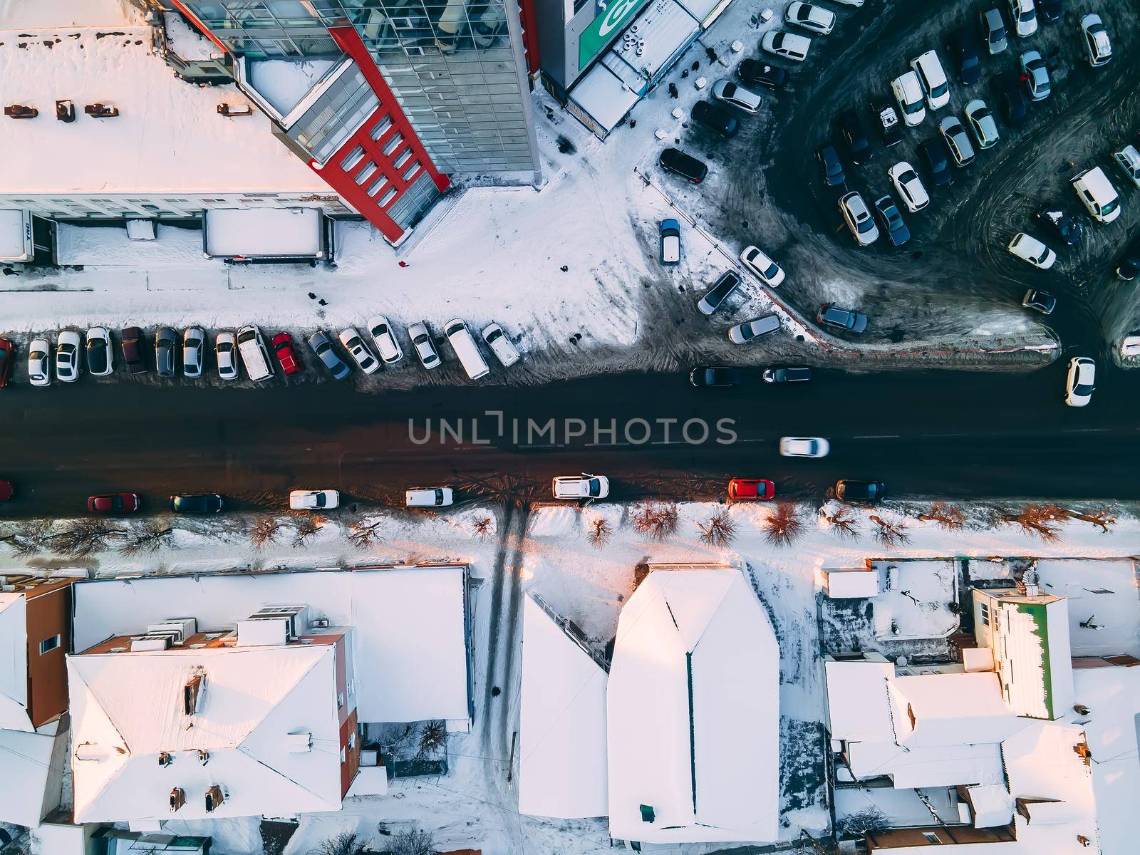 Aerial top down view of road in small european city with snow covered roofs at winter cloudy day