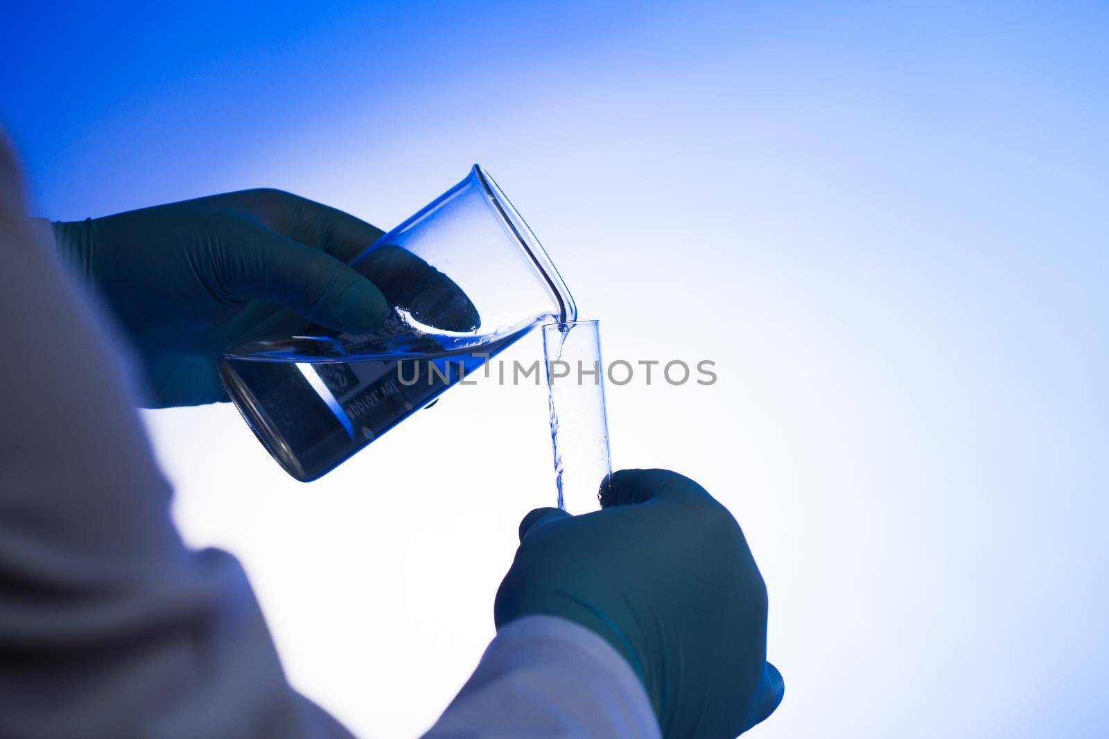 Male scientist pours liquid from beaker into test tube