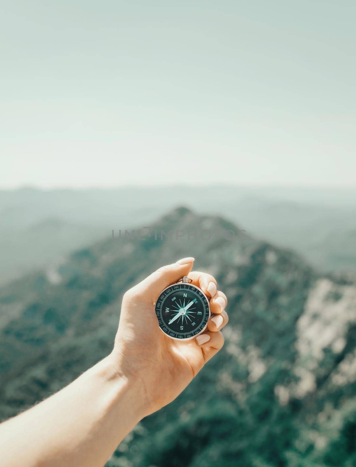Explorer woman searching direction with magnetic compass high in summer mountains, point of view. Concept of travel and hiking.