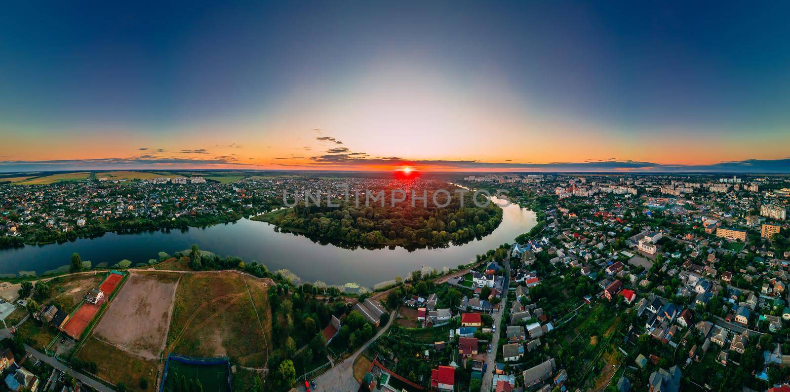 Aerial panoramic view of of small european city placed on river banks at summer sunny day with clouds, Kyiv region, Ukraine