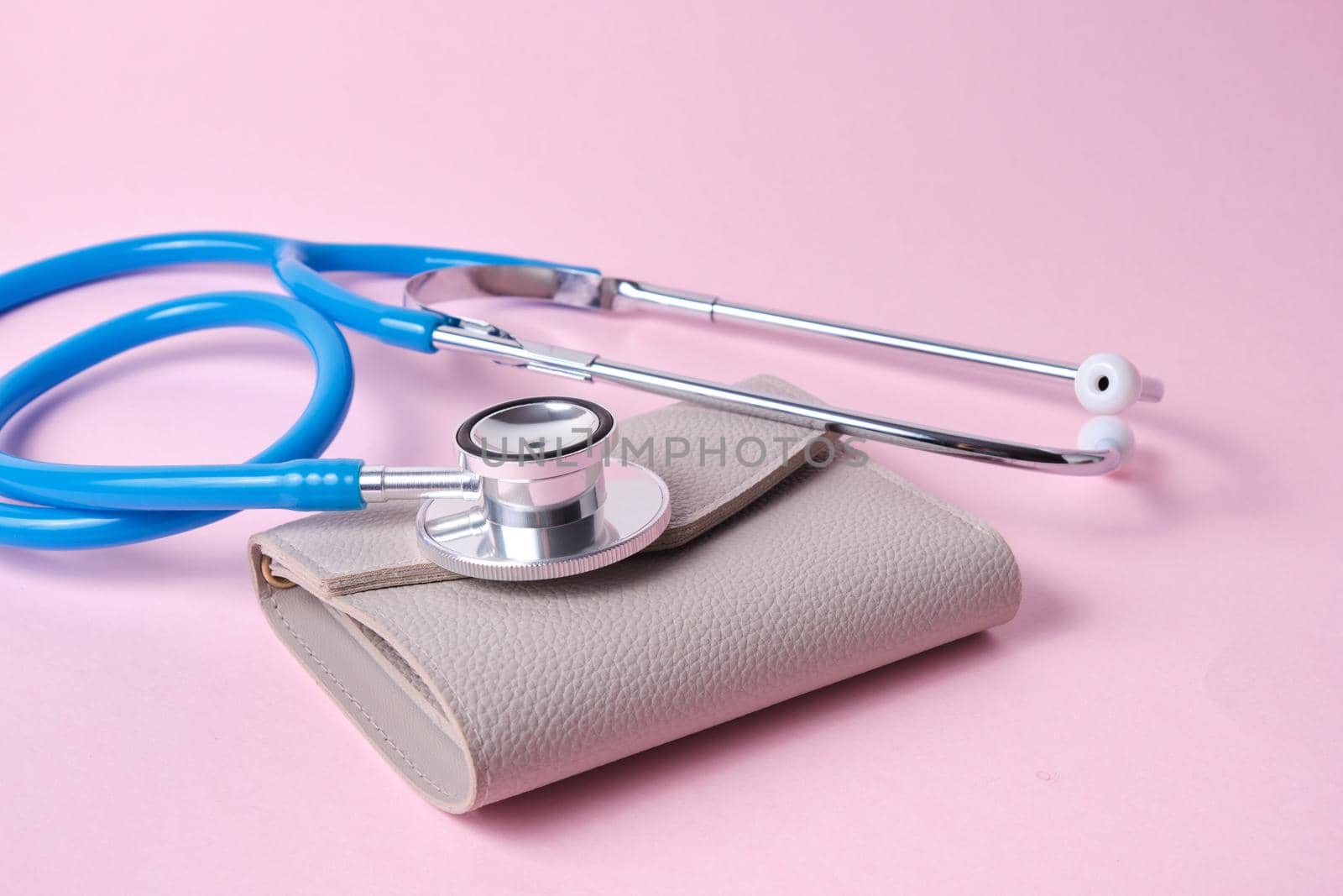 Stethoscope on an old wallet on pink background. the concept of monitoring income and expenses, savings and financial literacy