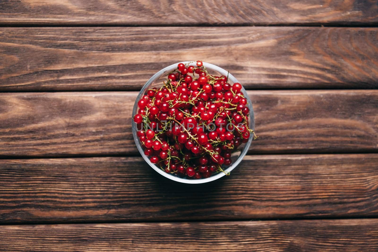 Fresh red currant in a bowl on a wooden background, top view.