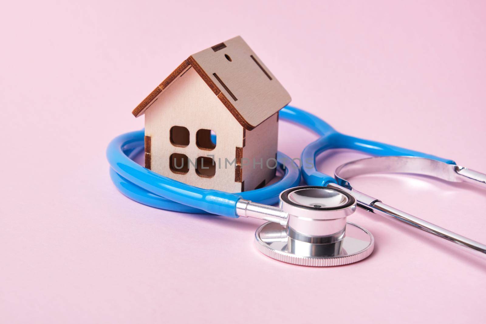 Medical stethoscope and toy house on a pink background with copy space by natashko