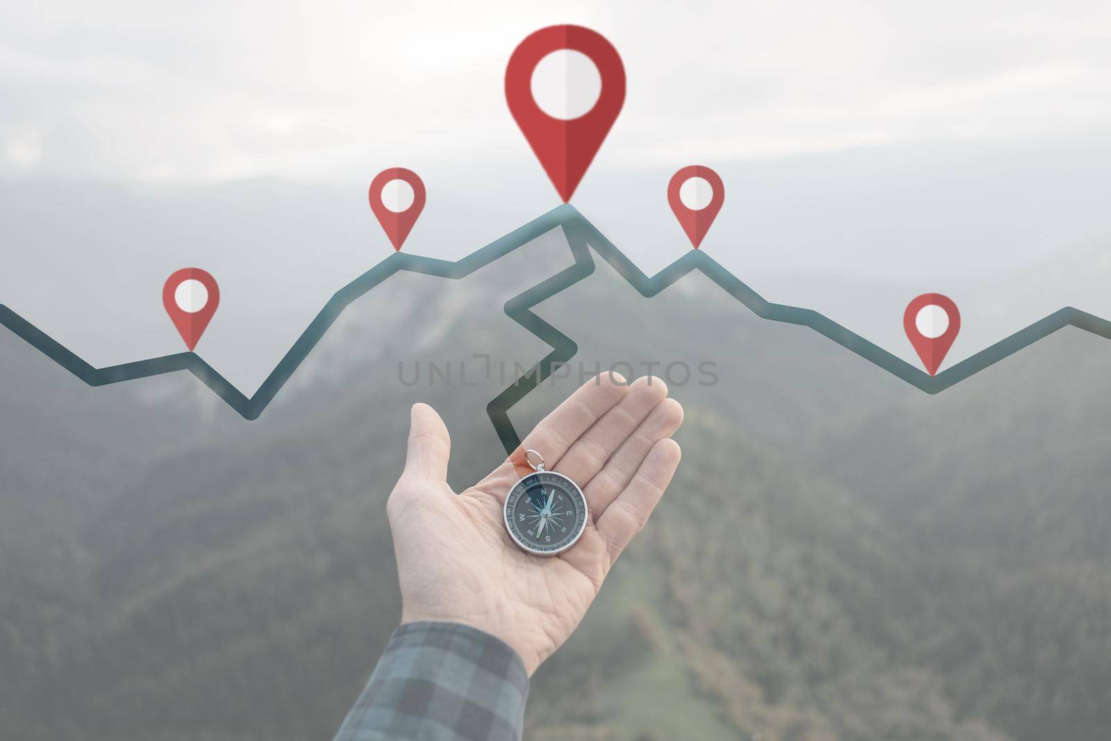 Male hand with compass and connected location pins on background of summer mountains, point of view. Navigation concept.