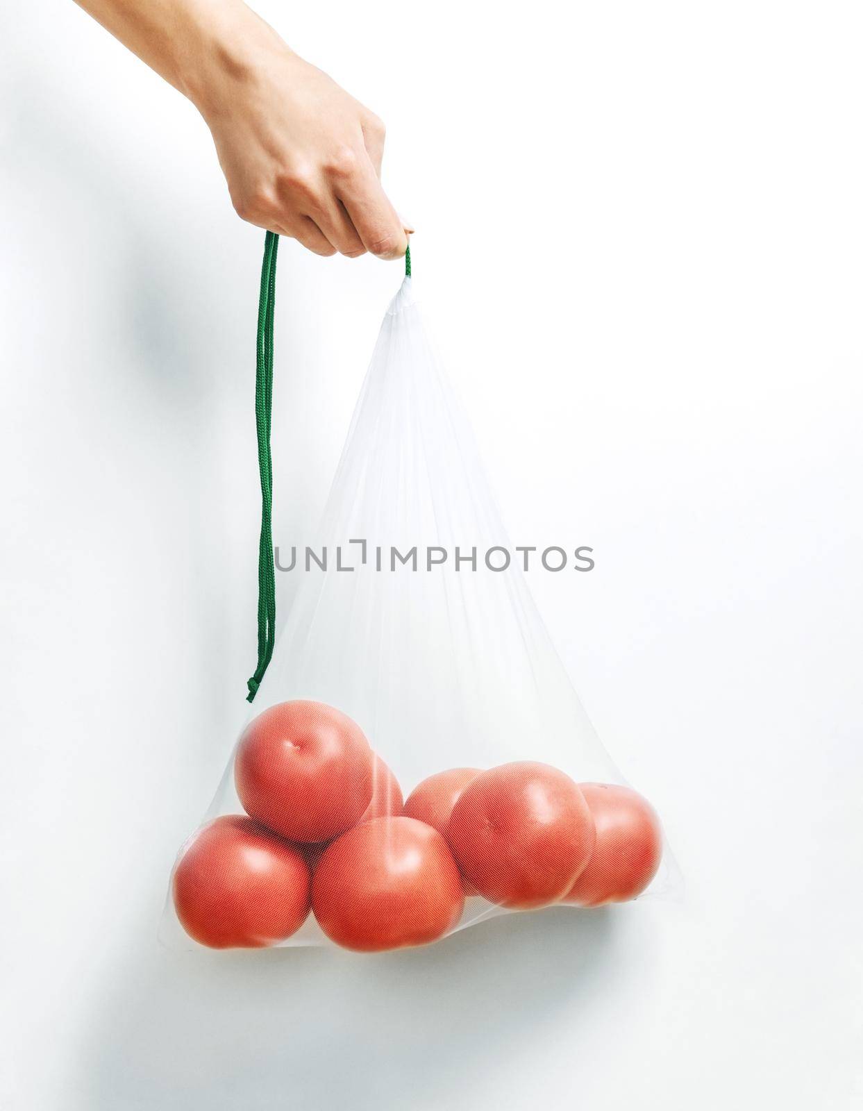 Hand holding a reusable eco bag with tomatoes. by alexAleksei