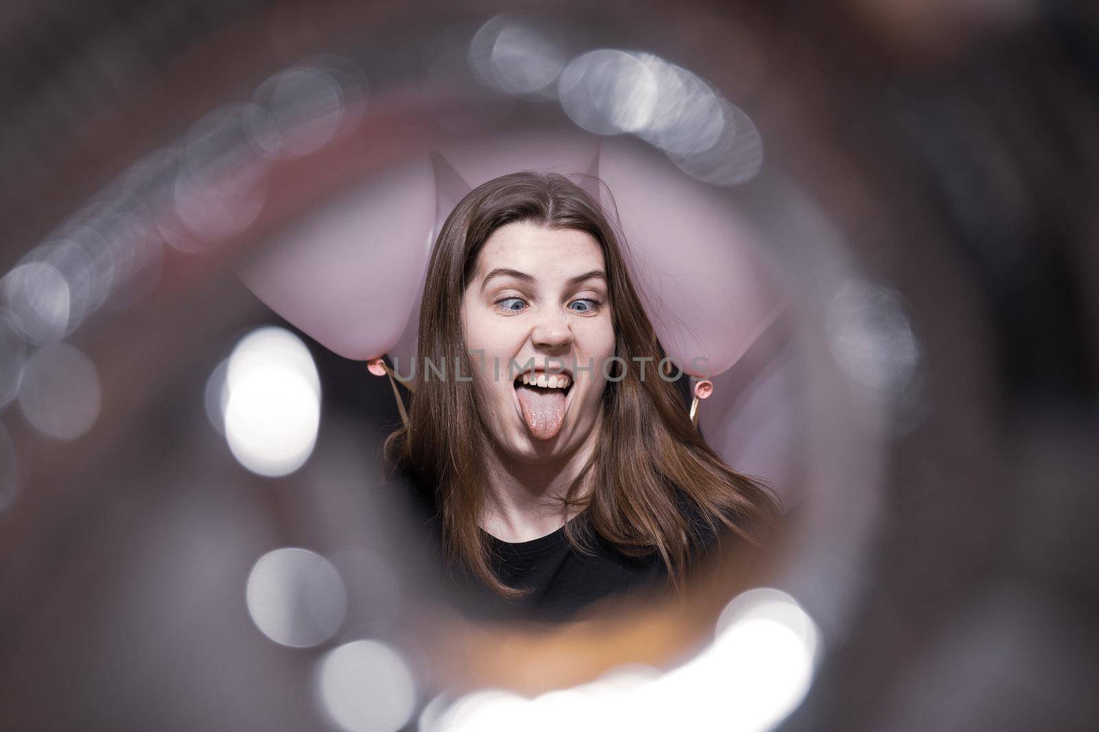 View through the tunnel. The face of a pretty girl with an emotion of joy that holds pink balloons on her birthday by lunarts