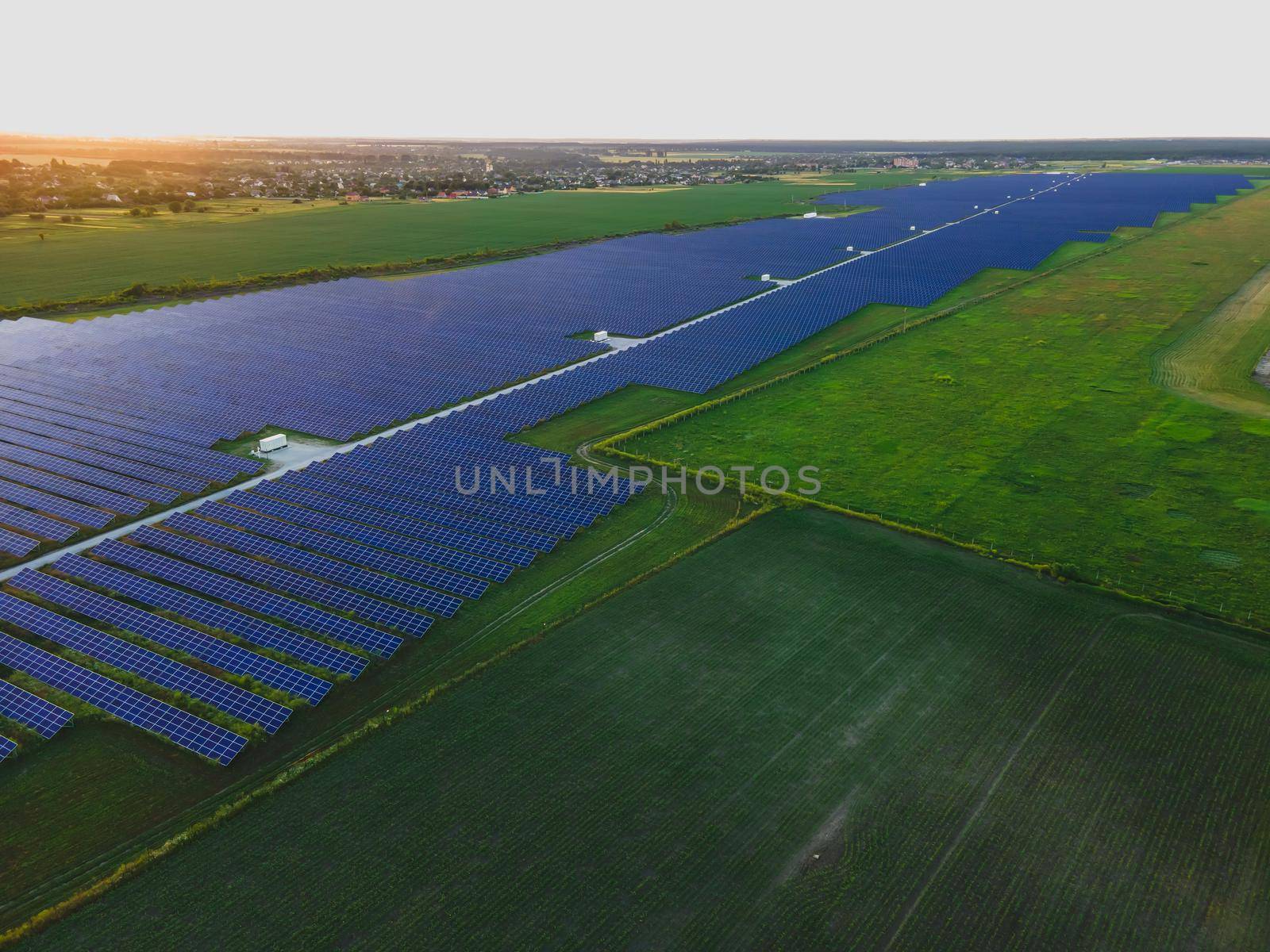 Aerial drone view of large solar panels at a solar farm at bright summer sunset. Solar cell power plants, colorful photo