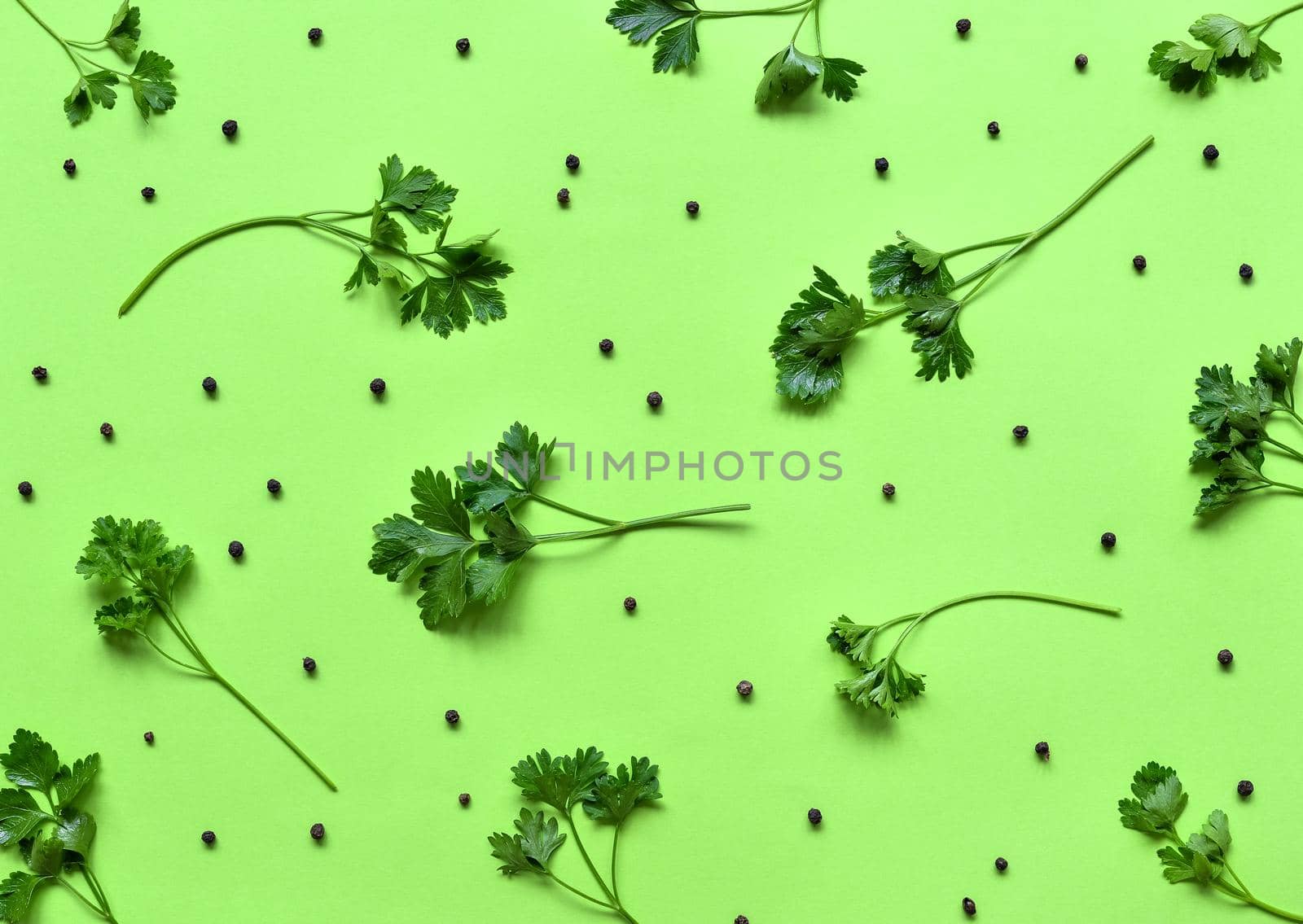 Parsley isolated. Pattern of parsley and black Pepper on a green background. Juicy bright green parsley leaves. Herbs and spices, flat lay, top view.