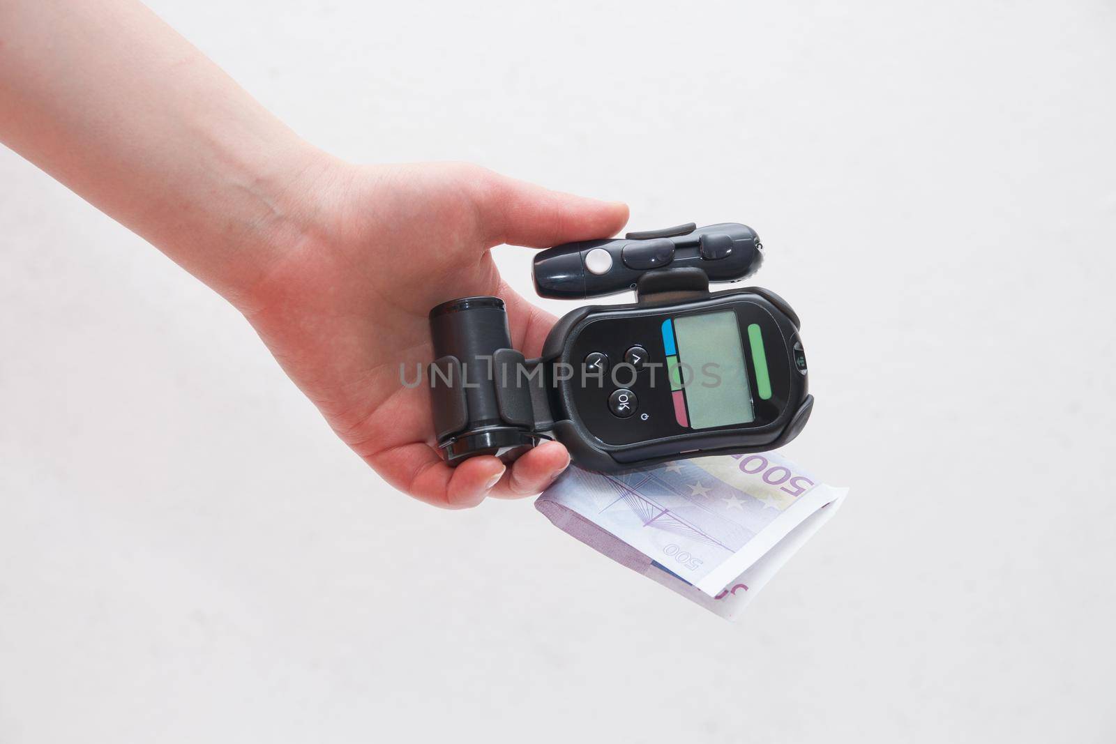 female hand holds a black glucometer and 500 euro white background