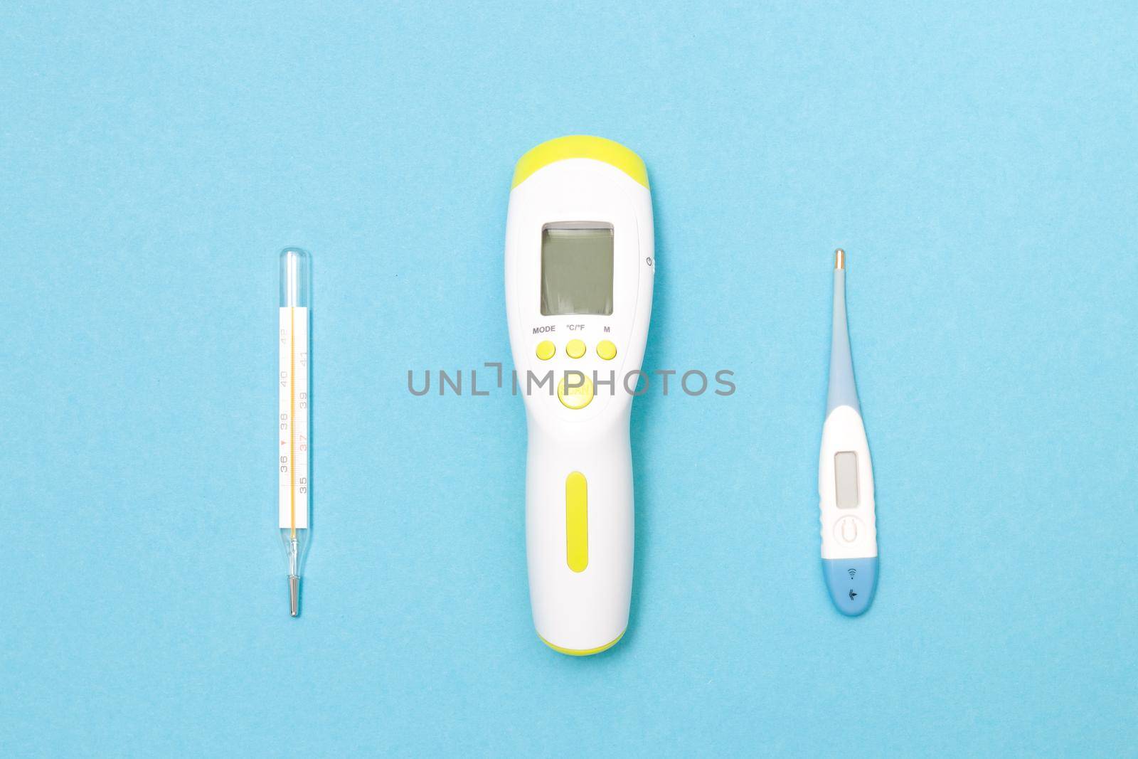 three thermometers on a blue background, electronic, mercury and infrared thermometers for measuring body temperature by natashko