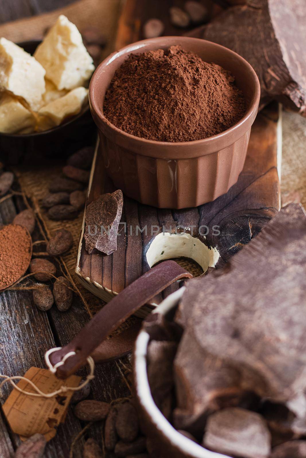 Unsweetened baking block chocolate, cocoa powder, cocoa butter and cocoa beans on old wooden background.